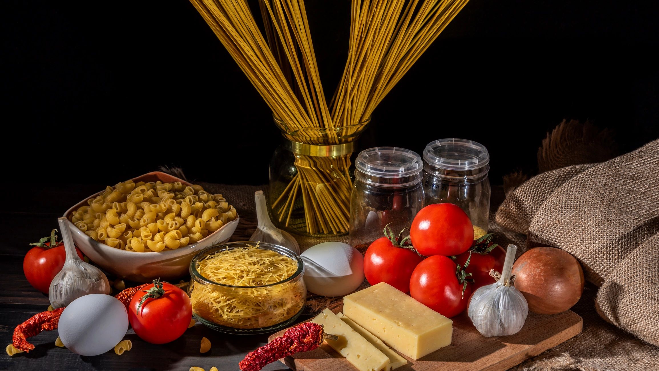 Pasta and vegetables styled on a dark surface with copy space