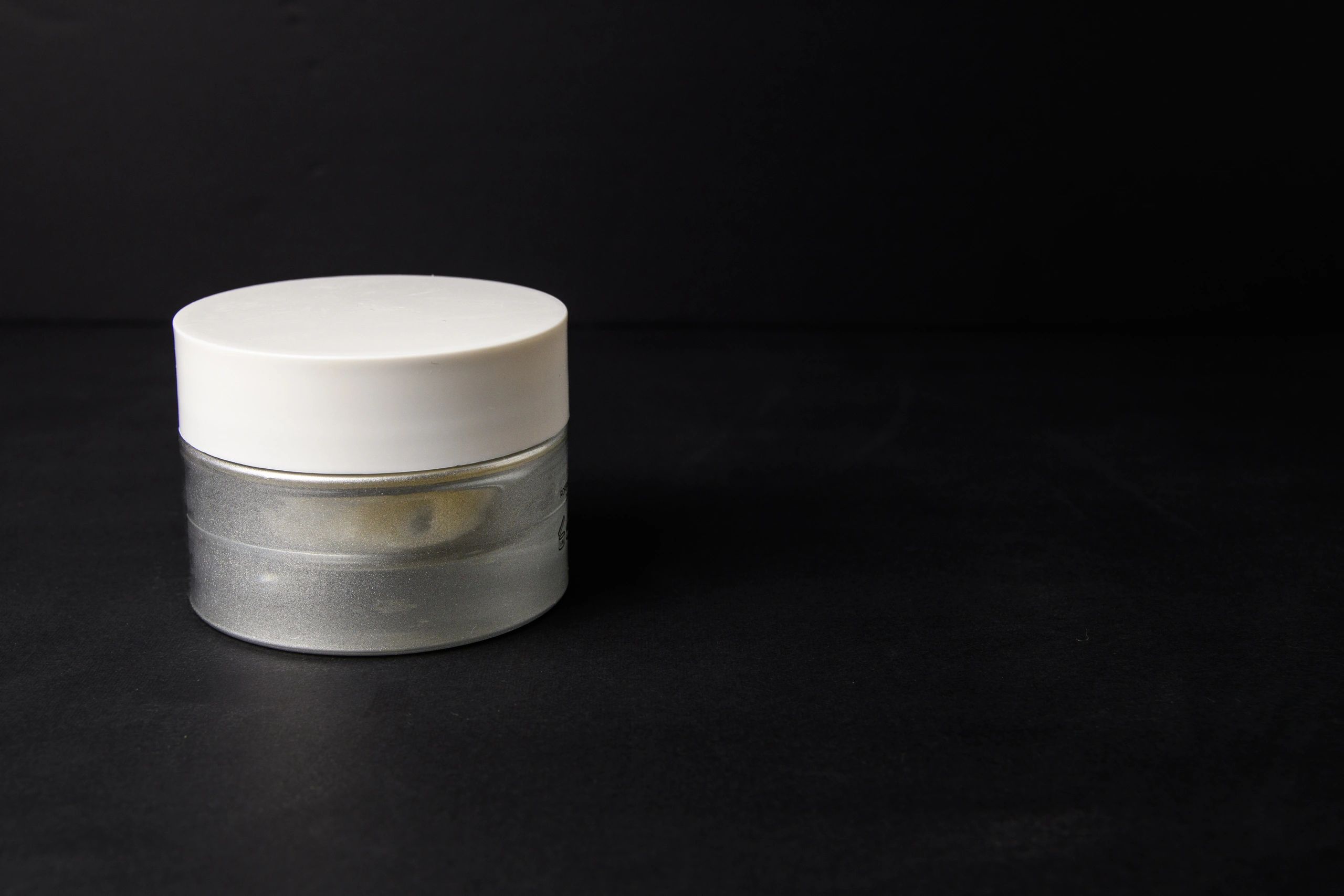 Minimal cosmetic jar on dark background with copy space